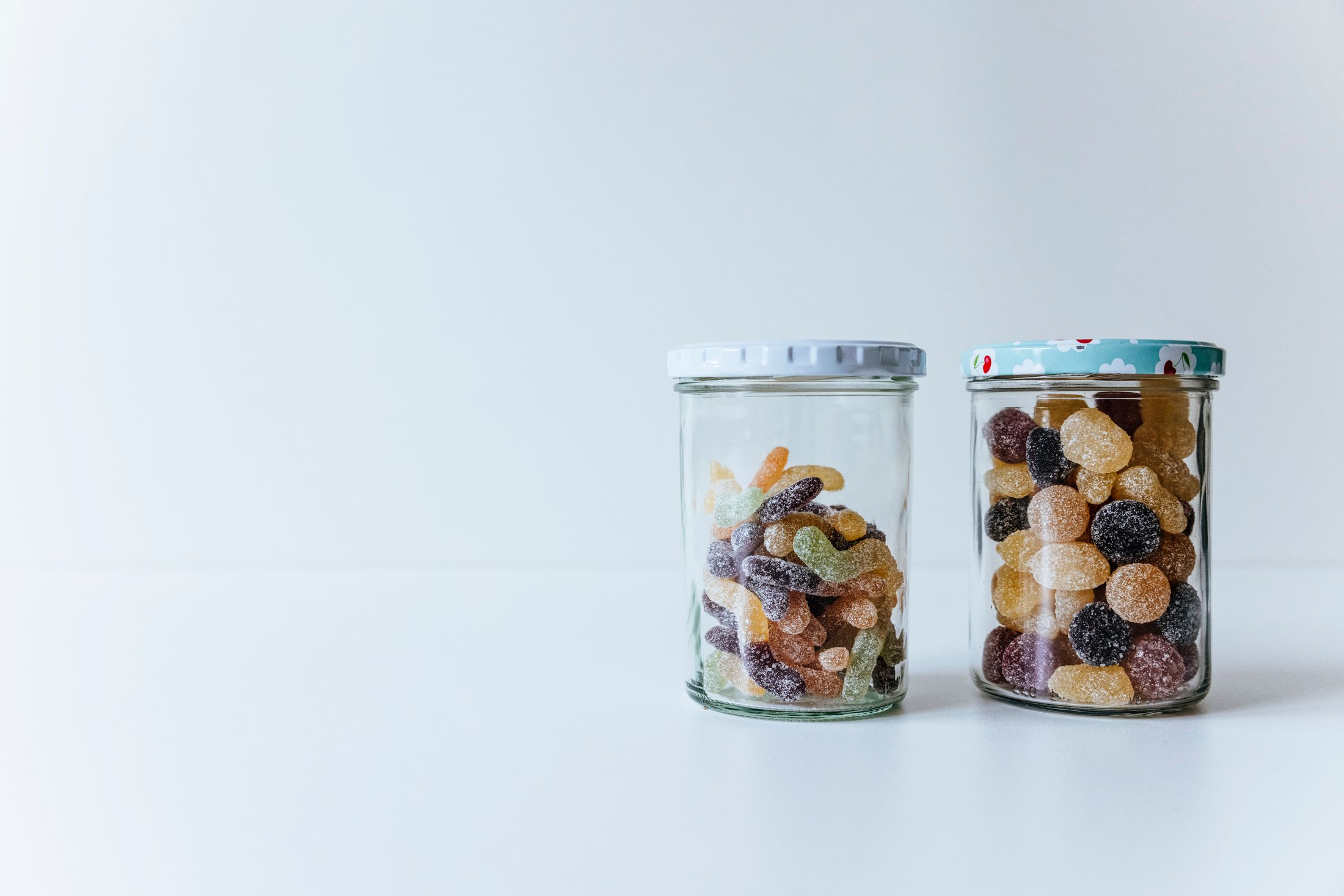 Gummy confectionery displayed in glass jars on a clean white surface